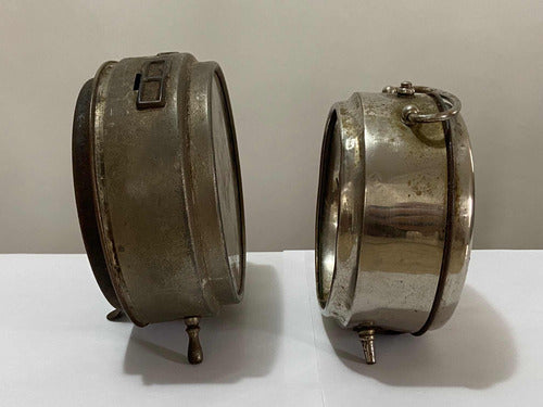 Two vintage silver-colored metal alarm clocks displayed side by side on a white surface against a plain background