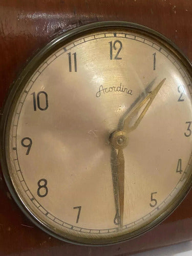 Close-up of an antique wooden table clock with cream face and vintage style hands showing 12:30