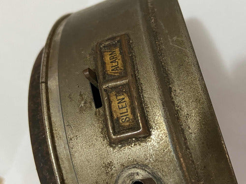 Close-up of a vintage silver metal alarm clock switch showing silent and alarm options on the side.