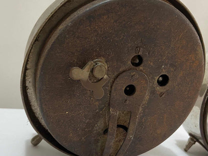 Close-up view of the back of a vintage silver-colored alarm clock showing winding key and metal details