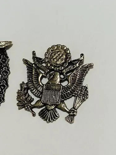 Metallic World War II era badge featuring an eagle with shield and olive branch on white background