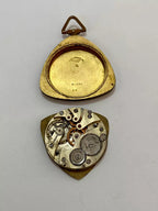 Antique pocket watch case opened showing vintage mechanical clock parts and intricate gears inside.
