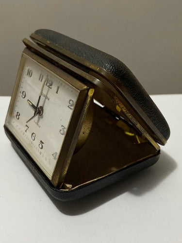 Vintage German travel alarm clock with leather case and classic white dial showing time and seconds hand